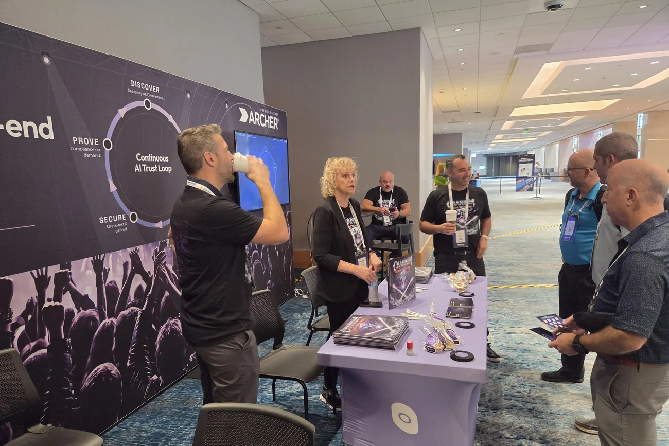 Cranium team talking with attendees at the Archer Summit 2026 booth, the AI Trust Loop wall behind them